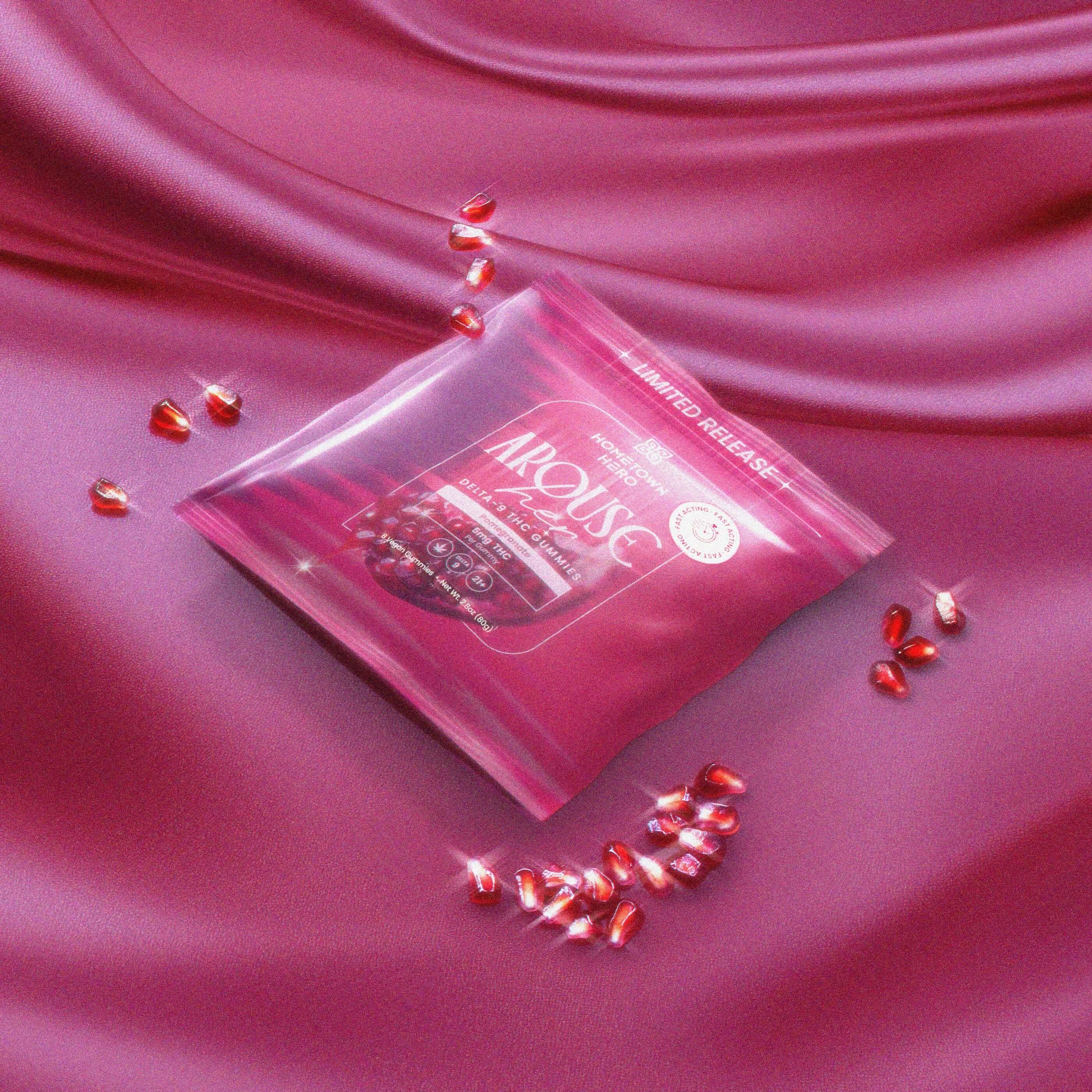 arouse her gummies on a pink sheet with glistening pomegranate seeds